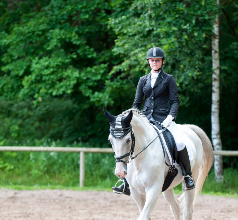 Teenage girl equestrian in dress uniform riding horseback on arena